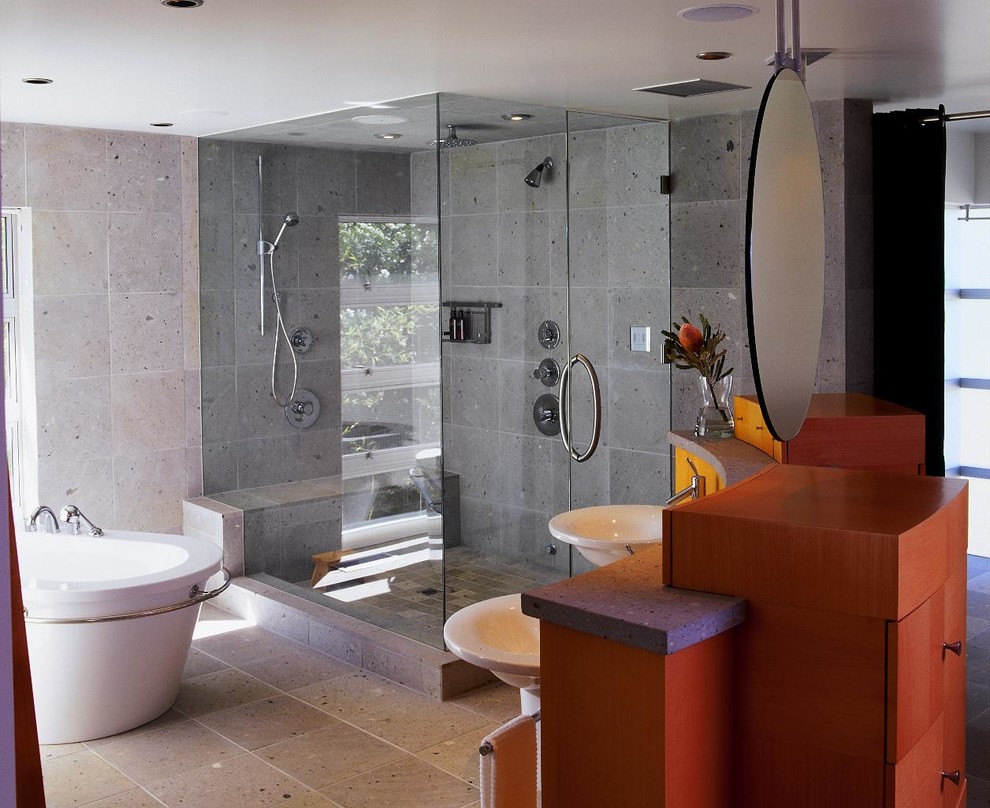 Inspiration för ett funkis badrum, med ett piedestal handfat, släta luckor, skåp i mellenmörkt trä, bänkskiva i betong, ett fristående badkar, en dubbeldusch, grå kakel, cementkakel, grå väggar och betonggolv