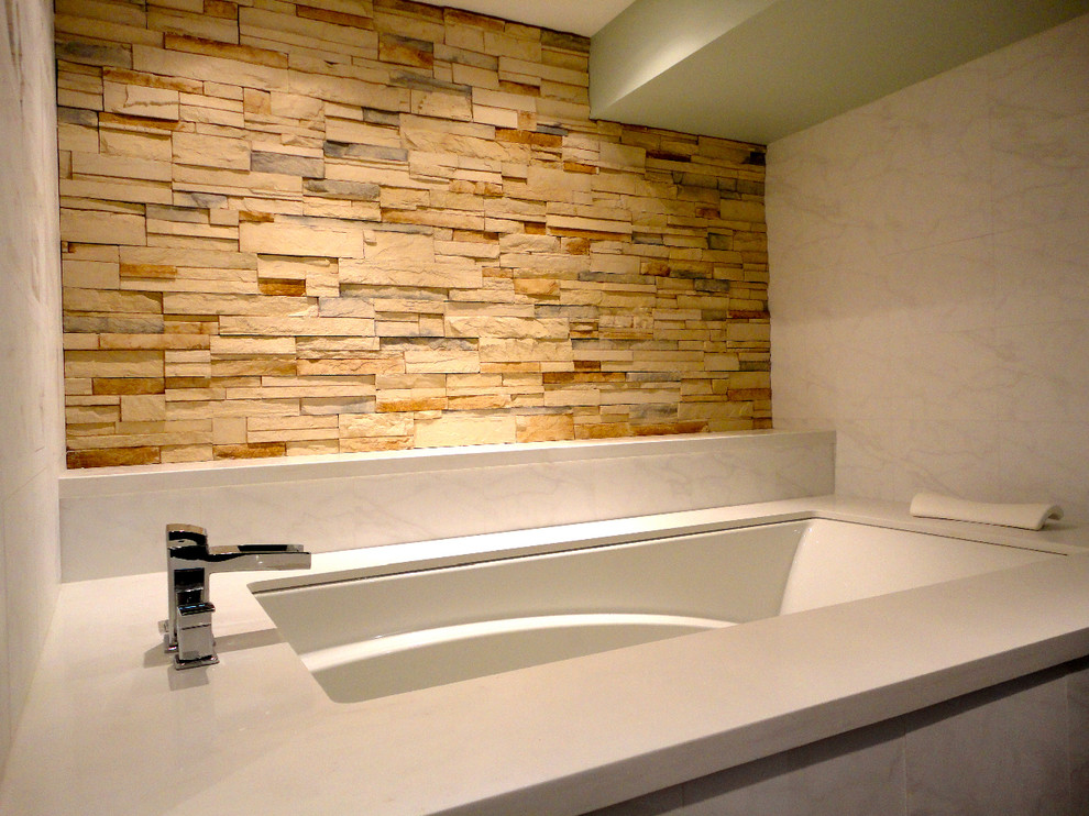 Cette photo montre une salle de bain principale tendance de taille moyenne avec une baignoire en alcôve, un carrelage beige, un carrelage de pierre et un mur beige.