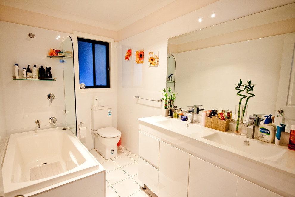 Ispirazione per una stanza da bagno classica con ante lisce, ante bianche, vasca da incasso, vasca/doccia, WC a due pezzi e piastrelle bianche