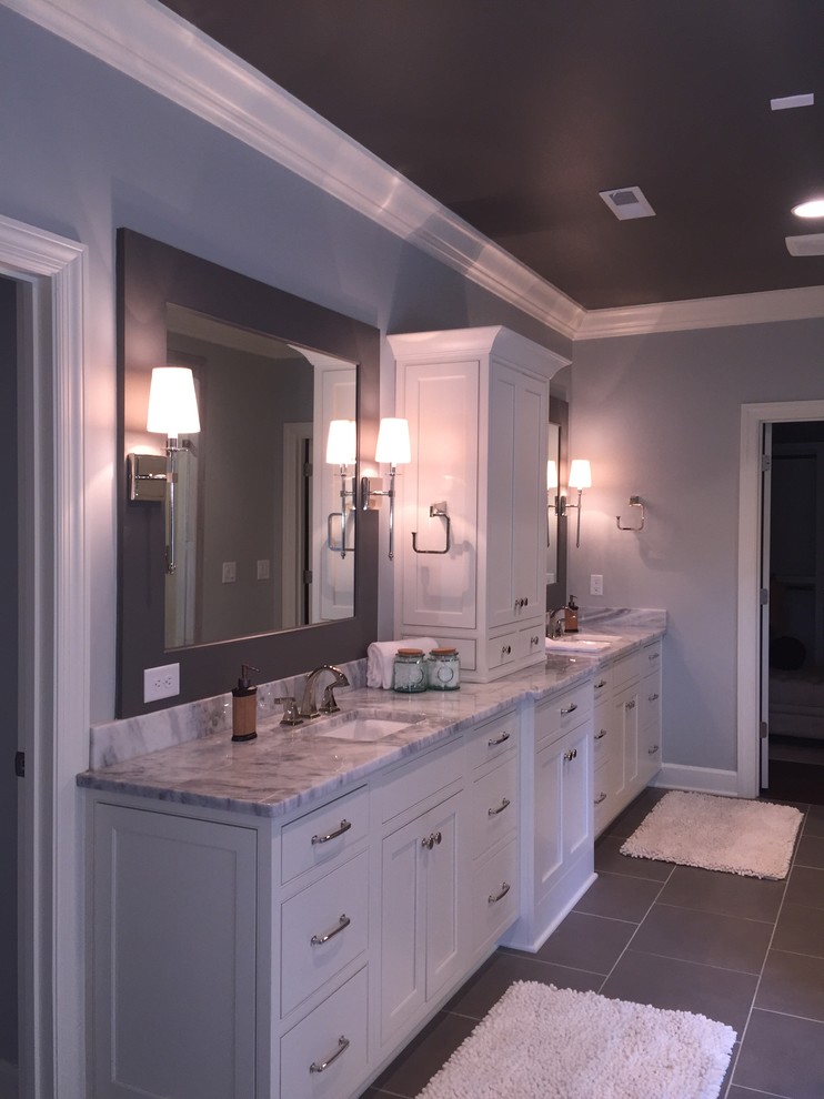 Klassisk inredning av ett badrum, med luckor med profilerade fronter, vita skåp, ett fristående badkar, en dubbeldusch, grå kakel, porslinskakel, blå väggar, klinkergolv i porslin, ett undermonterad handfat, marmorbänkskiva, grått golv och dusch med gångjärnsdörr