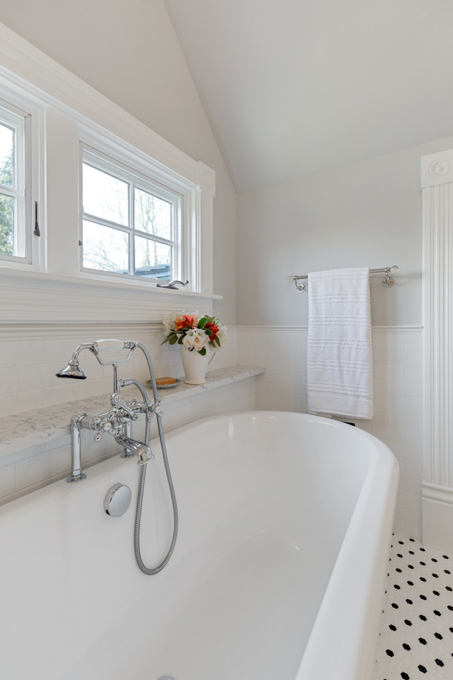 На фото: главная ванная комната в викторианском стиле с серыми фасадами, отдельно стоящей ванной, раздельным унитазом, белой плиткой, плиткой кабанчик, серыми стенами, полом из керамической плитки, врезной раковиной, столешницей из искусственного кварца, разноцветным полом, душем с распашными дверями и белой столешницей