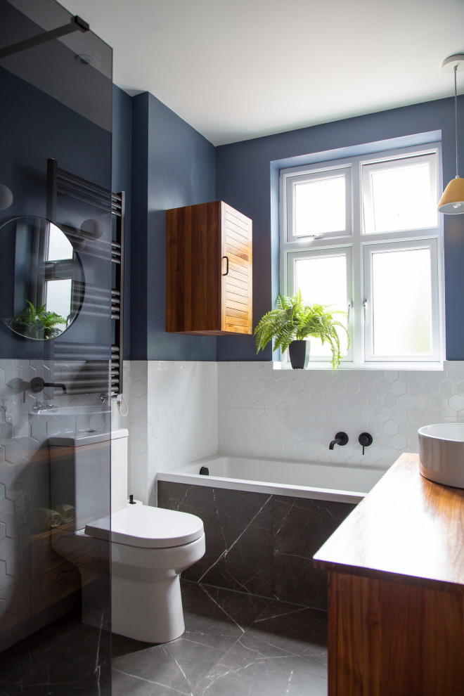 Источник вдохновения для домашнего уюта: маленькая детская ванная комната в стиле фьюжн с фасадами с филенкой типа жалюзи, коричневыми фасадами, накладной ванной, душевой комнатой, инсталляцией, белой плиткой, керамогранитной плиткой, синими стенами, полом из керамогранита, столешницей из дерева, черным полом, коричневой столешницей, тумбой под одну раковину, напольной тумбой и деревянным потолком для на участке и в саду