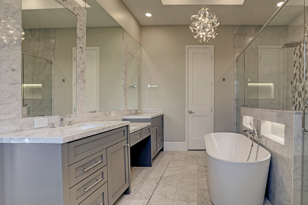 На фото: огромная главная ванная комната в современном стиле с фасадами в стиле шейкер, серыми фасадами, отдельно стоящей ванной, двойным душем, унитазом-моноблоком, серой плиткой, мраморной плиткой, серыми стенами, мраморным полом, врезной раковиной, мраморной столешницей, белым полом, душем с распашными дверями и белой столешницей с