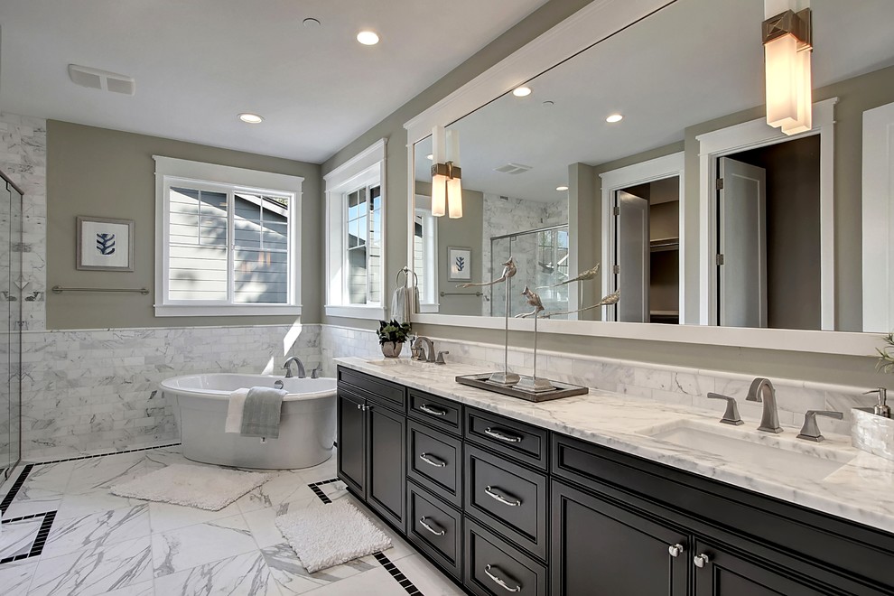 Diseño de cuarto de baño principal de estilo americano con armarios con rebordes decorativos, puertas de armario negras, bañera exenta, paredes grises y lavabo bajoencimera