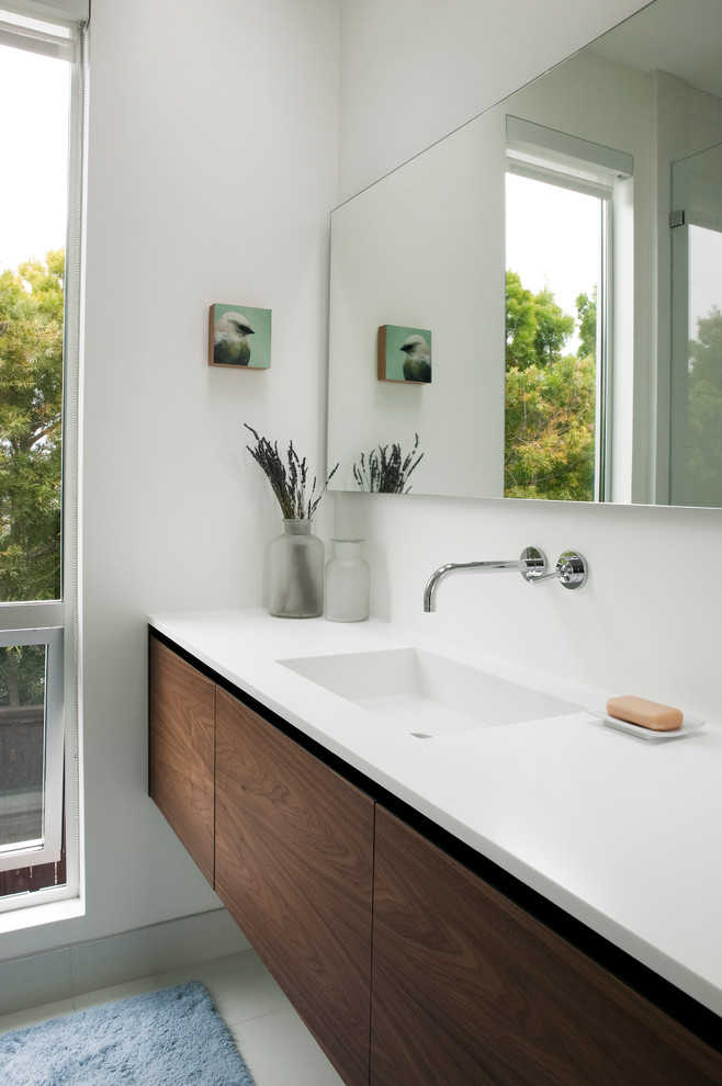 На фото: главная ванная комната в современном стиле с монолитной раковиной, темными деревянными фасадами, мраморной столешницей и белыми стенами