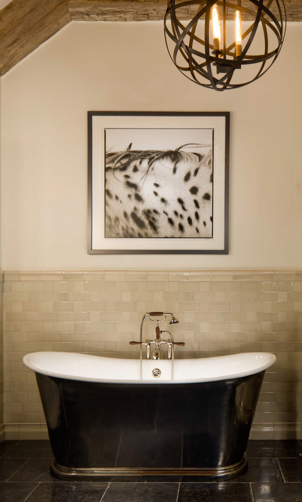 На фото: ванная комната в стиле рустика с отдельно стоящей ванной и черным полом с
