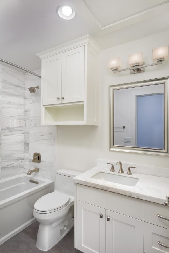 Cette photo montre une salle d'eau chic de taille moyenne avec un placard à porte shaker, des portes de placard blanches, un combiné douche/baignoire, un mur blanc, un lavabo encastré, une baignoire en alcôve, WC à poser, un carrelage gris, du carrelage en marbre, un plan de toilette en marbre, un sol gris, une cabine de douche avec un rideau, un plan de toilette blanc, meuble simple vasque et meuble-lavabo encastré.