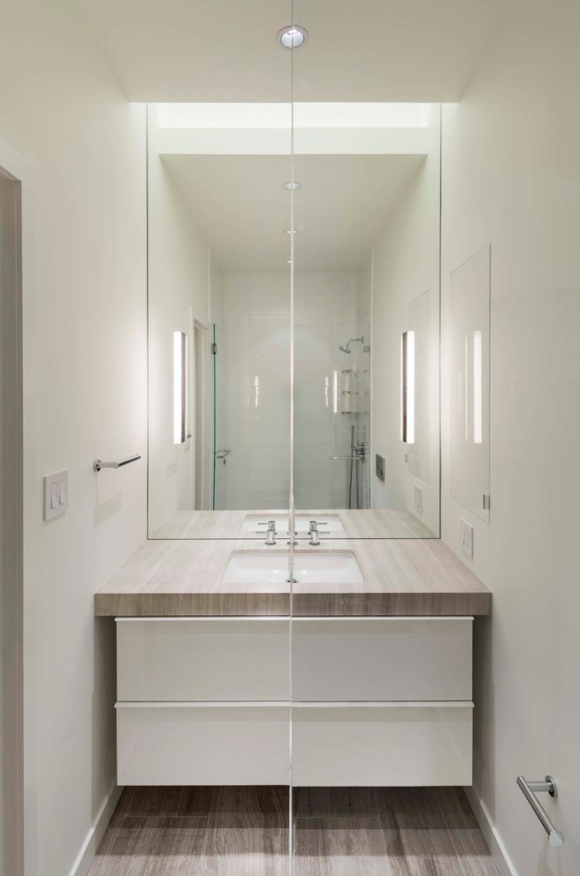 Exemple d'une petite salle de bain moderne avec un placard à porte plane, des portes de placard blanches, une douche ouverte, WC suspendus, un carrelage blanc, des carreaux de porcelaine, un mur blanc, un sol en marbre, un lavabo encastré, un plan de toilette en marbre, un sol gris et une cabine de douche à porte battante.