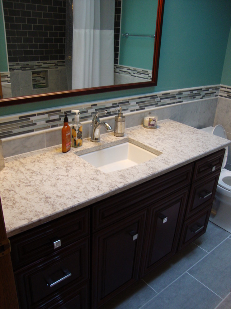 Mid-sized elegant master gray tile and stone tile porcelain tile alcove bathtub photo in Chicago with an undermount sink, raised-panel cabinets, dark wood cabinets, quartz countertops and a two-piece toilet