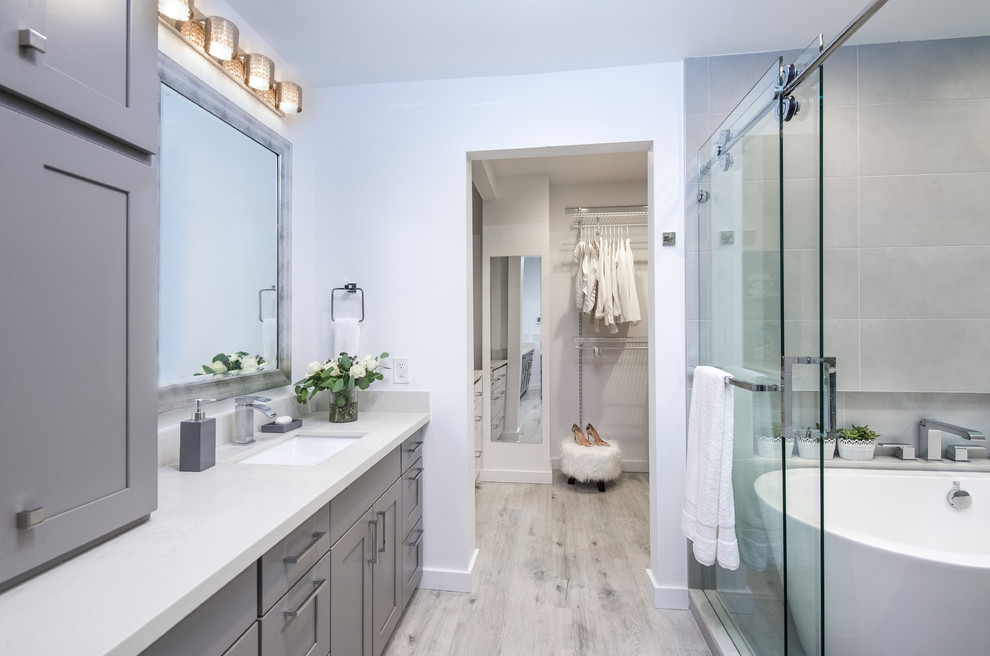 Idéer för stora vintage en-suite badrum, med släta luckor, grå skåp, ett fristående badkar, en öppen dusch, en toalettstol med hel cisternkåpa, vit kakel, stenhäll, blå väggar, ljust trägolv, ett nedsänkt handfat och bänkskiva i akrylsten
