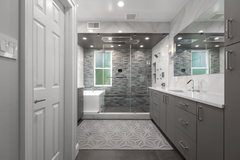 На фото: ванная комната среднего размера в стиле модернизм с плоскими фасадами, серыми фасадами, душем над ванной, унитазом-моноблоком, белой плиткой, керамической плиткой, белыми стенами, душевой кабиной, подвесной раковиной, столешницей из кварцита, коричневым полом, душем с распашными дверями, белой столешницей, сиденьем для душа, тумбой под одну раковину, встроенной тумбой и многоуровневым потолком