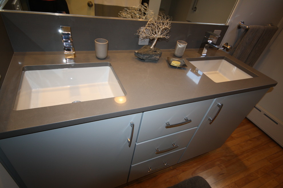 Example of a trendy medium tone wood floor bathroom design in Boston with an undermount sink, flat-panel cabinets, gray cabinets, quartz countertops, a two-piece toilet and gray walls