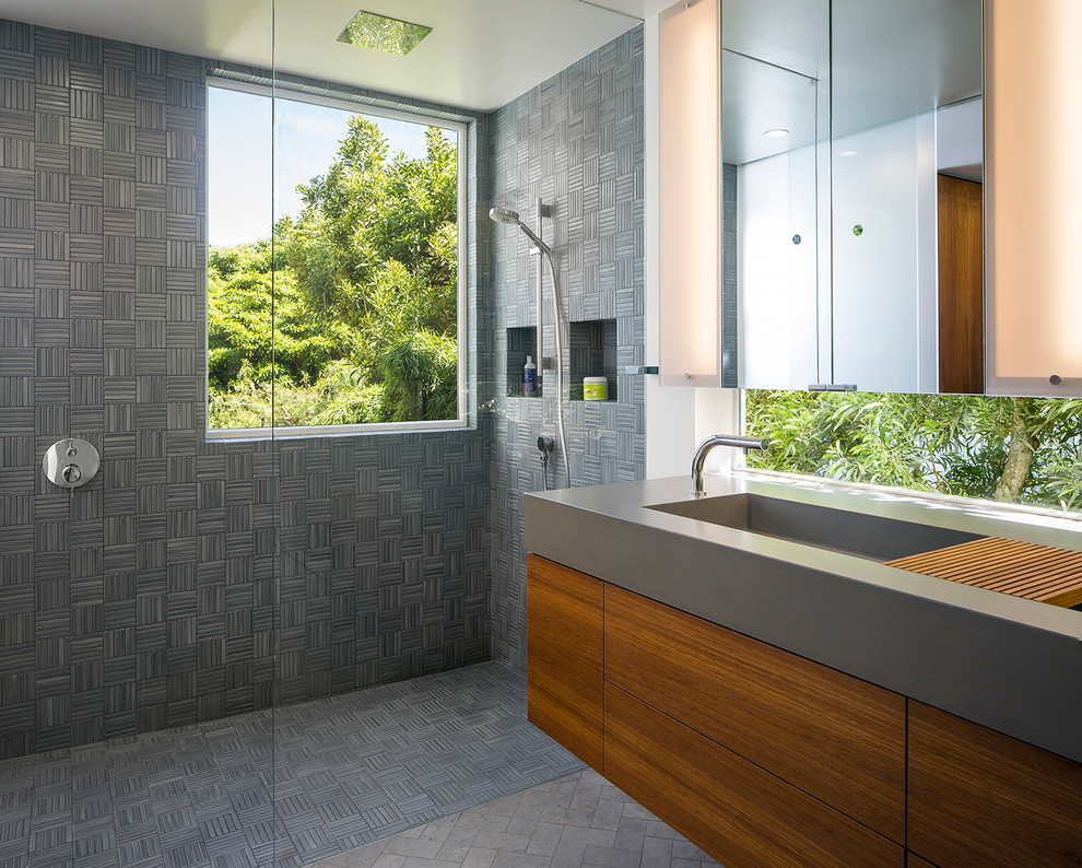 This is an example of a contemporary bathroom in San Francisco with flat-panel cabinets, medium wood cabinets, concrete worktops, a built-in shower, grey tiles, ceramic tiles, limestone flooring and a trough sink.