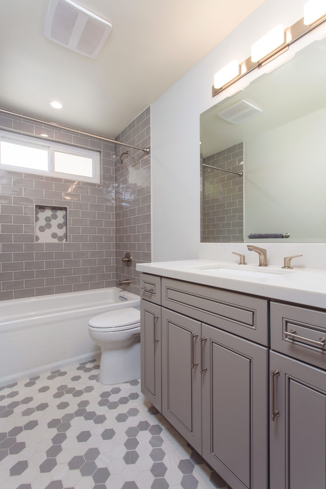 Пример оригинального дизайна: маленькая детская ванная комната в стиле неоклассика (современная классика) с фасадами с выступающей филенкой, серыми фасадами, ванной в нише, душем над ванной, унитазом-моноблоком, серой плиткой, плиткой кабанчик, серыми стенами, полом из мозаичной плитки, врезной раковиной, столешницей из искусственного кварца, серым полом и шторкой для ванной для на участке и в саду