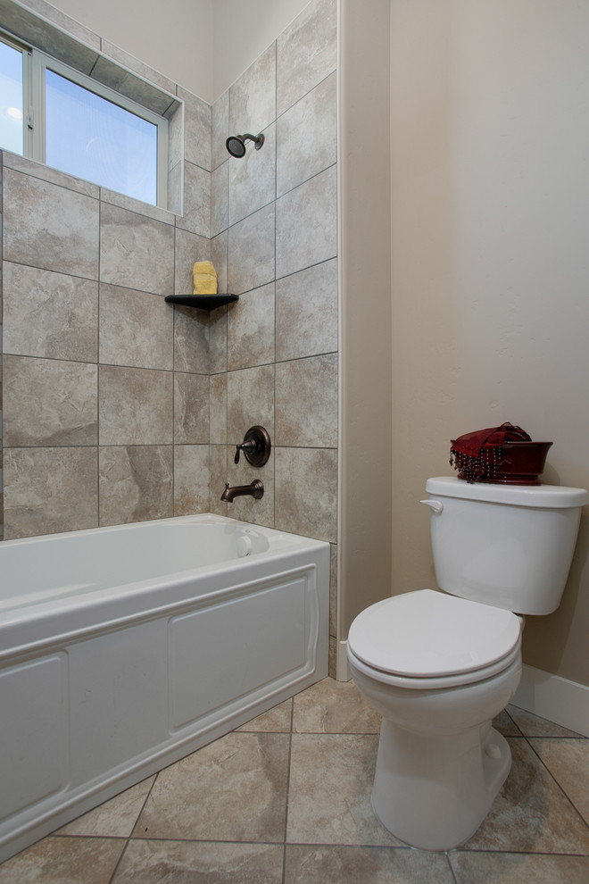 Design ideas for a medium sized traditional family bathroom in Boise with a vessel sink, raised-panel cabinets, medium wood cabinets, quartz worktops, a corner bath, a shower/bath combination, a one-piece toilet, grey tiles, glass tiles, grey walls and travertine flooring.