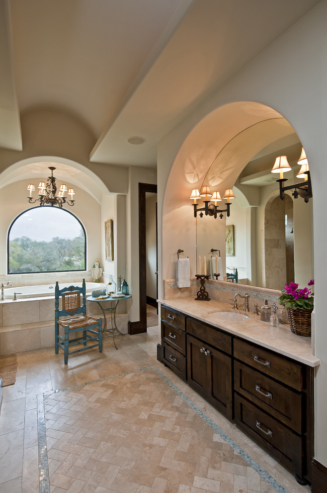 Example of a huge tuscan master beige tile and glass tile travertine floor drop-in bathtub design in Austin with an undermount sink, shaker cabinets, dark wood cabinets, a one-piece toilet and white walls