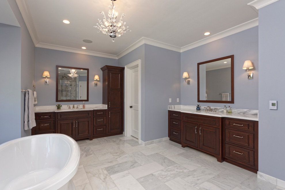 Aménagement d'une salle de bain classique en bois foncé avec un placard à porte affleurante, une baignoire indépendante, un carrelage blanc, un carrelage de pierre, un sol en marbre, un lavabo encastré et un plan de toilette en marbre.