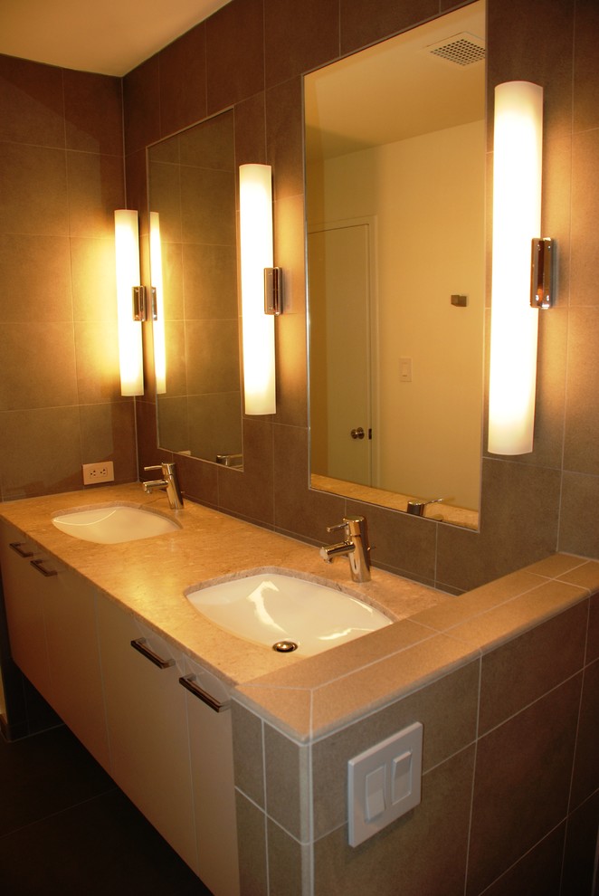 Inredning av ett modernt stort en-suite badrum, med släta luckor, vita skåp, en dusch/badkar-kombination, ett undermonterad handfat, en toalettstol med separat cisternkåpa, brun kakel, porslinskakel, bruna väggar, klinkergolv i porslin och bänkskiva i kalksten