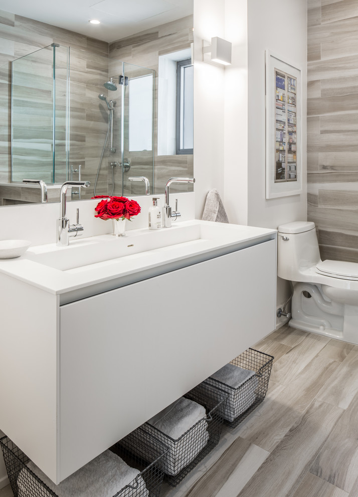 Inspiration for a contemporary ensuite bathroom in New York with flat-panel cabinets, white cabinets, an alcove bath, a corner shower, a one-piece toilet, beige tiles, porcelain tiles, white walls, porcelain flooring, a wall-mounted sink and engineered stone worktops.