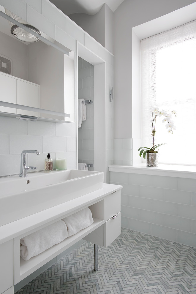На фото: ванная комната в современном стиле с плоскими фасадами, белыми фасадами, белой плиткой, серыми стенами, настольной раковиной, серым полом и открытым душем с