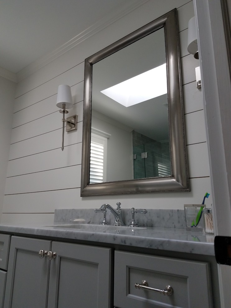Стильный дизайн: ванная комната среднего размера в стиле неоклассика (современная классика) с фасадами с утопленной филенкой, серыми фасадами, душем в нише, унитазом-моноблоком, белыми стенами, мраморным полом, душевой кабиной, врезной раковиной, мраморной столешницей, серым полом, душем с распашными дверями, серой плиткой и плиткой кабанчик - последний тренд