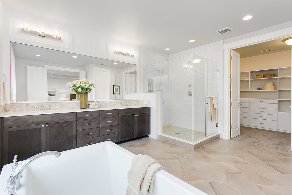 Photo of a large traditional ensuite bathroom in Seattle with shaker cabinets, dark wood cabinets, a freestanding bath, a corner shower, grey tiles, porcelain tiles, grey walls, porcelain flooring, a submerged sink and solid surface worktops.