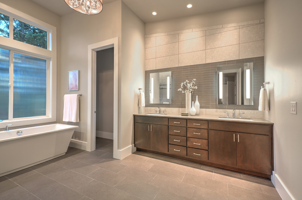 Пример оригинального дизайна: большая главная ванная комната в современном стиле с врезной раковиной, плоскими фасадами, коричневыми фасадами, отдельно стоящей ванной, серой плиткой, серыми стенами и серым полом