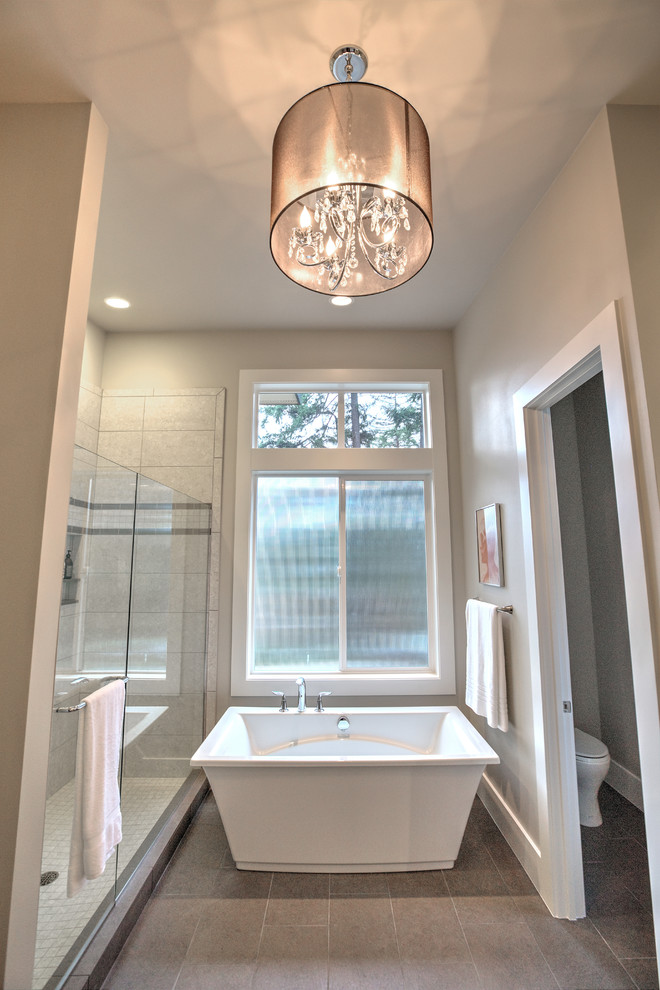 Diseño de cuarto de baño principal contemporáneo grande con bañera exenta, ducha empotrada, sanitario de una pieza, baldosas y/o azulejos grises, paredes grises y suelo de baldosas de porcelana