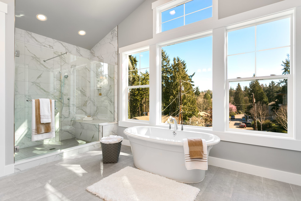 Foto på ett stort amerikanskt en-suite badrum, med ett fristående badkar, en dusch i en alkov, flerfärgad kakel, grå väggar, grått golv och dusch med gångjärnsdörr