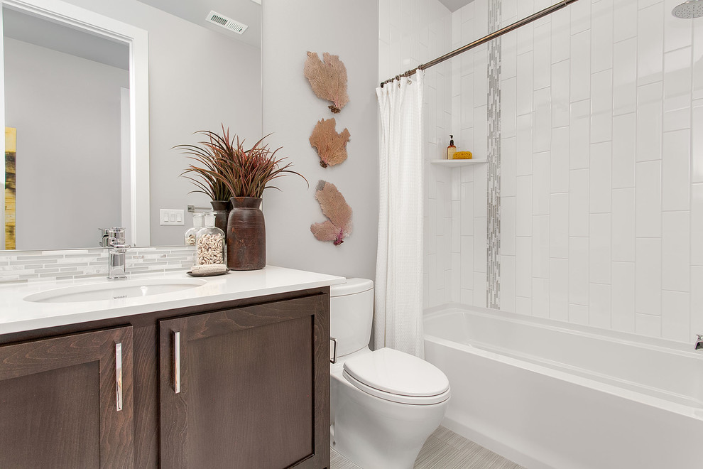 Inspiration for a medium sized classic bathroom in Seattle with a submerged sink, recessed-panel cabinets, medium wood cabinets, quartz worktops, a shower/bath combination, a two-piece toilet, multi-coloured tiles, glass tiles and grey walls.