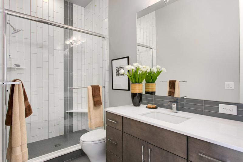 Inspiration for a mid-sized contemporary master gray tile and glass tile porcelain tile alcove shower remodel in Seattle with flat-panel cabinets, dark wood cabinets, a two-piece toilet, gray walls, an undermount sink and quartz countertops