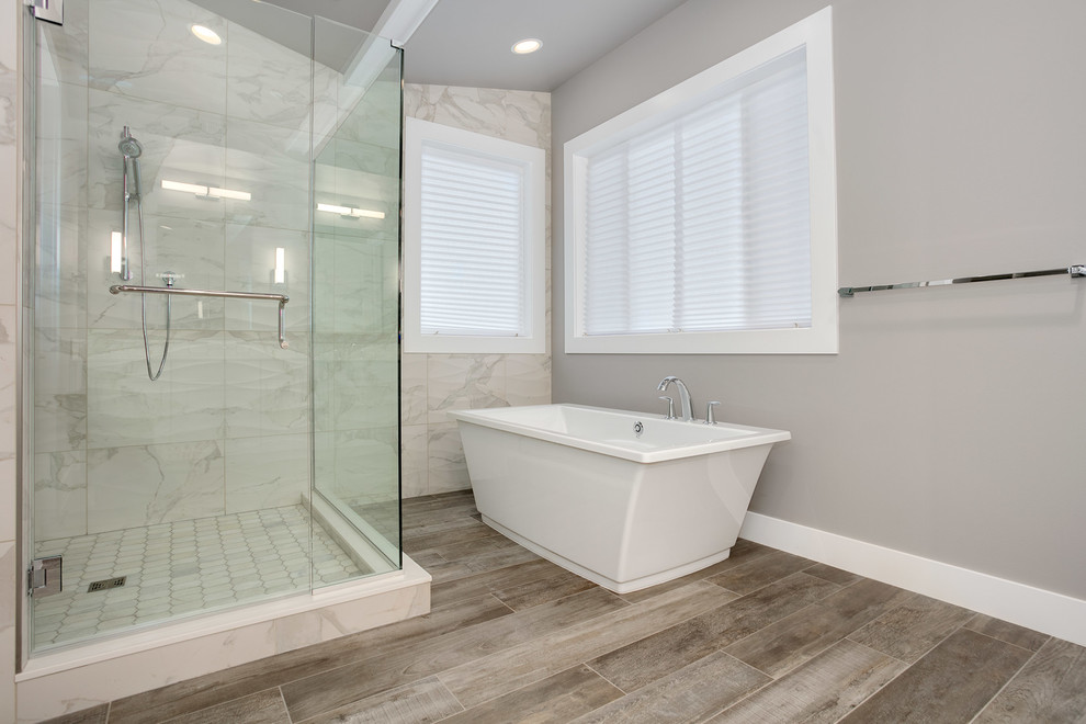 Inspiration pour une grande salle de bain principale design avec un mur gris, un sol gris, une baignoire indépendante, une douche d'angle, un carrelage gris et une cabine de douche à porte battante.