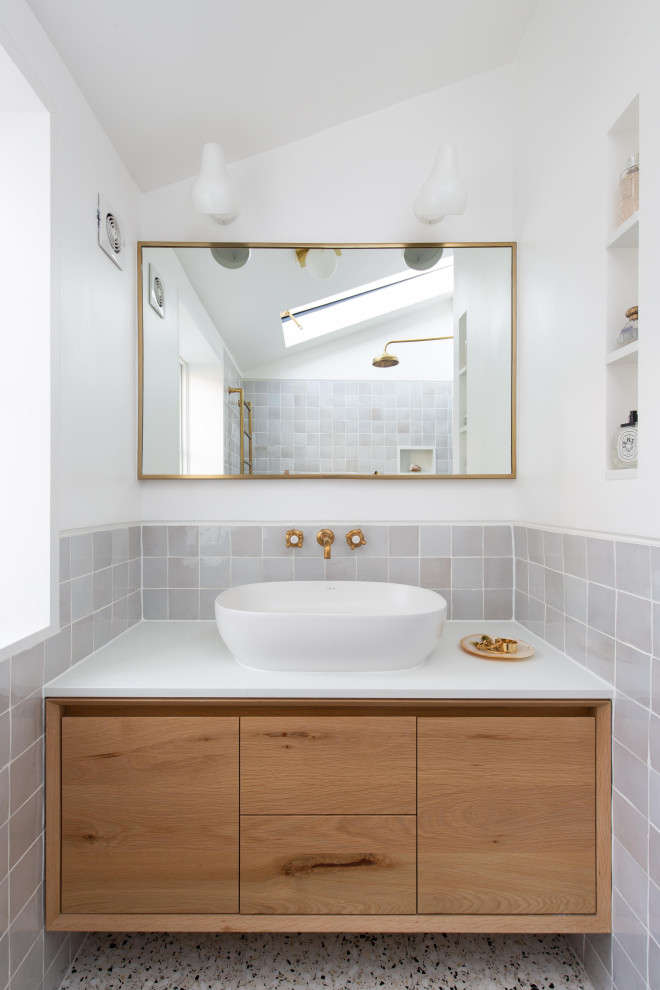 Inspiration pour une salle d'eau traditionnelle en bois clair de taille moyenne avec un placard à porte plane, un carrelage gris, des carreaux de porcelaine, un mur blanc, une vasque, un sol beige et un plan de toilette blanc.