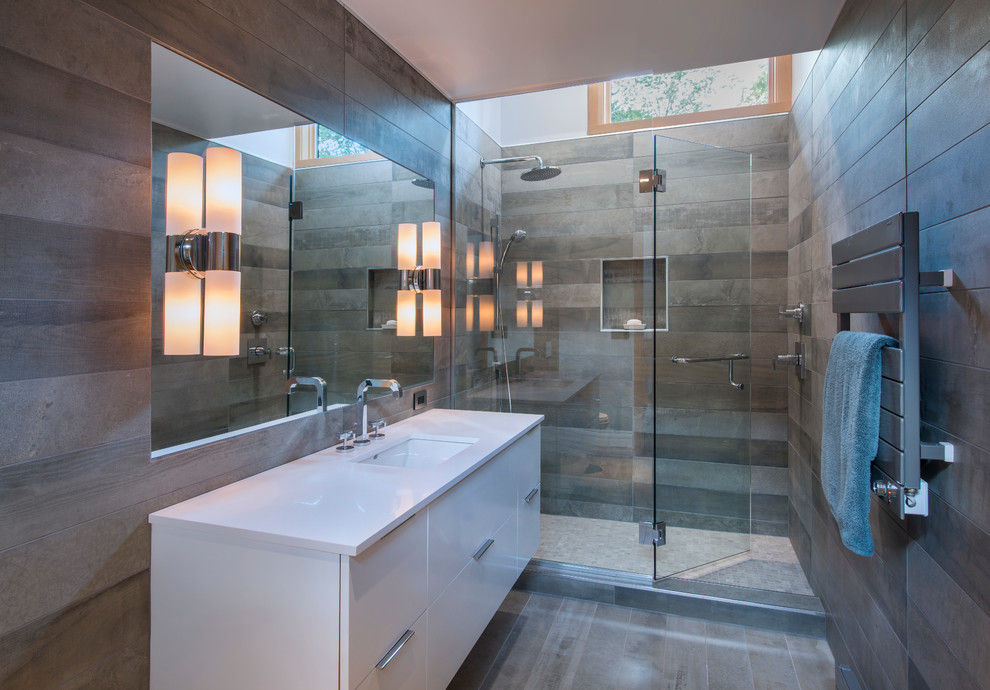 Large trendy 3/4 gray tile and ceramic tile ceramic tile alcove shower photo in Burlington with flat-panel cabinets, white cabinets, gray walls, solid surface countertops, a one-piece toilet and an undermount sink
