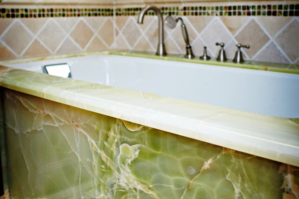 Aménagement d'une salle de bain principale classique en bois foncé de taille moyenne avec un placard à porte affleurante, une baignoire encastrée, un mur gris, un lavabo encastré, un plan de toilette en onyx et un plan de toilette vert.