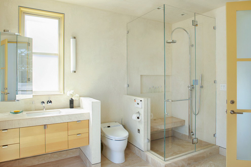 サンフランシスコにあるコンテンポラリースタイルのおしゃれな浴室 (アンダーカウンター洗面器、フラットパネル扉のキャビネット、淡色木目調キャビネット、コーナー設置型シャワー、一体型トイレ	、ベージュのタイル) の写真