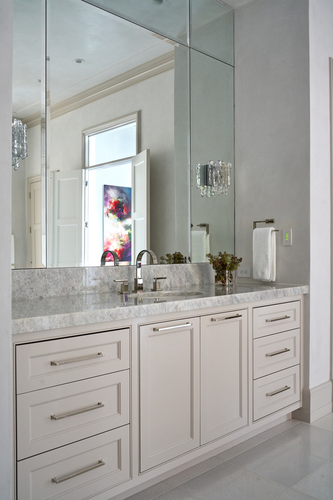 Inredning av ett klassiskt grå grått badrum, med vita väggar, luckor med profilerade fronter, beige skåp, ett undermonterad handfat och grått golv