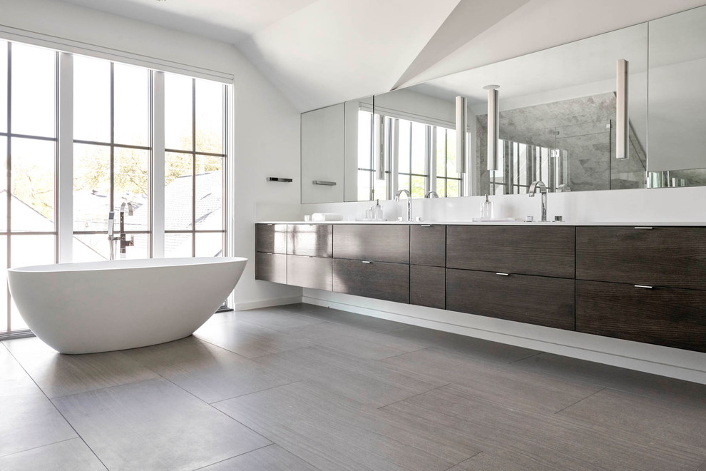 Immagine di una grande stanza da bagno padronale design con ante lisce, ante in legno bruno, vasca freestanding, doccia a filo pavimento, WC a due pezzi, piastrelle grigie, piastrelle bianche, piastrelle in pietra, pareti bianche, pavimento in gres porcellanato, lavabo a bacinella e top in quarzo composito