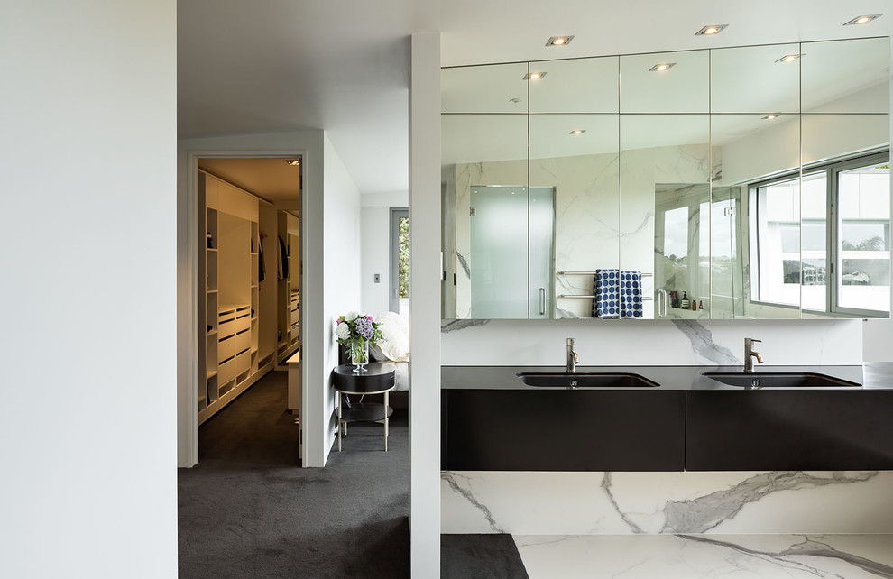 This is an example of a modern ensuite bathroom in Auckland with black cabinets, white tiles, marble tiles, white walls, a hinged door and black worktops.