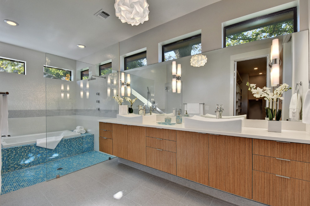 Bathroom - mid-sized contemporary master blue tile and glass tile ceramic tile and gray floor bathroom idea in Austin with flat-panel cabinets, medium tone wood cabinets, a one-piece toilet, gray walls, a vessel sink, solid surface countertops and white countertops