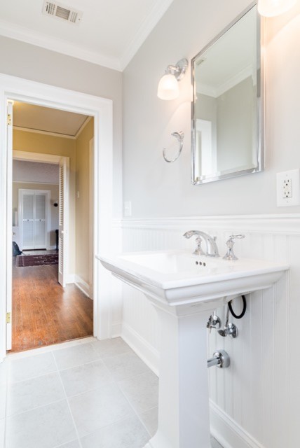 Klassisk inredning av ett litet badrum för barn, med ett badkar i en alkov, en dusch/badkar-kombination, en toalettstol med separat cisternkåpa, vit kakel, keramikplattor, vita väggar och ett piedestal handfat
