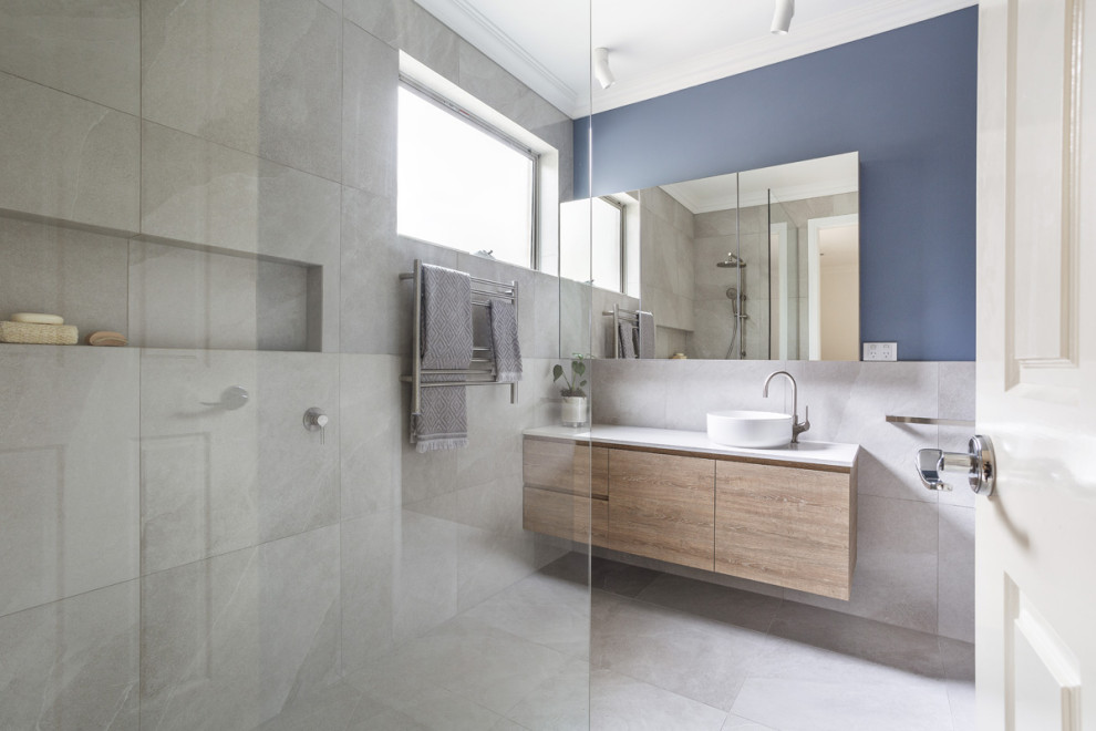 Medium sized contemporary bathroom in Melbourne with light wood cabinets, a corner shower, grey tiles, porcelain tiles, blue walls, porcelain flooring, a console sink, engineered stone worktops, grey floors and white worktops.