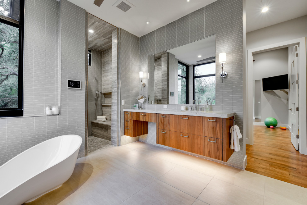 Idée de décoration pour une salle de bain design en bois brun avec un placard à porte plane, une baignoire indépendante, un carrelage gris, un lavabo encastré, un sol gris et un plan de toilette gris.