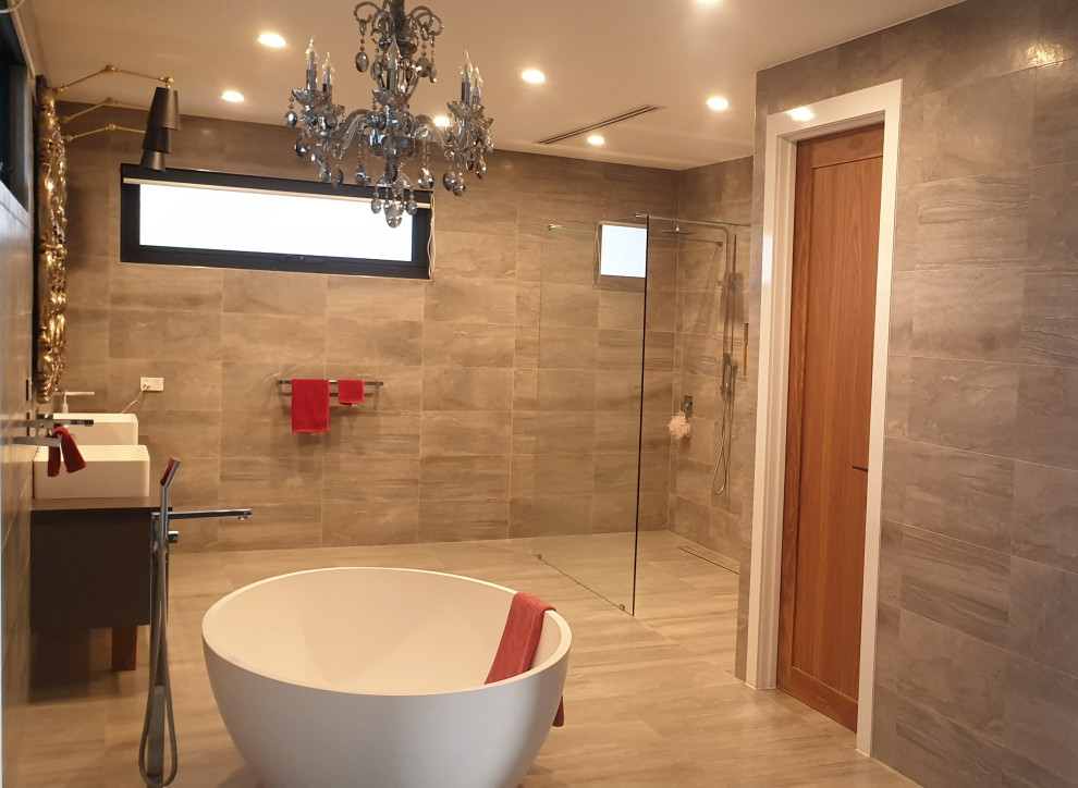 Photo of a large contemporary ensuite bathroom in Melbourne with flat-panel cabinets, grey cabinets, a freestanding bath, a walk-in shower, a wall mounted toilet, grey tiles, porcelain tiles, grey walls, porcelain flooring, a vessel sink, concrete worktops, grey floors, an open shower, black worktops, an enclosed toilet, double sinks, a floating vanity unit and a coffered ceiling.