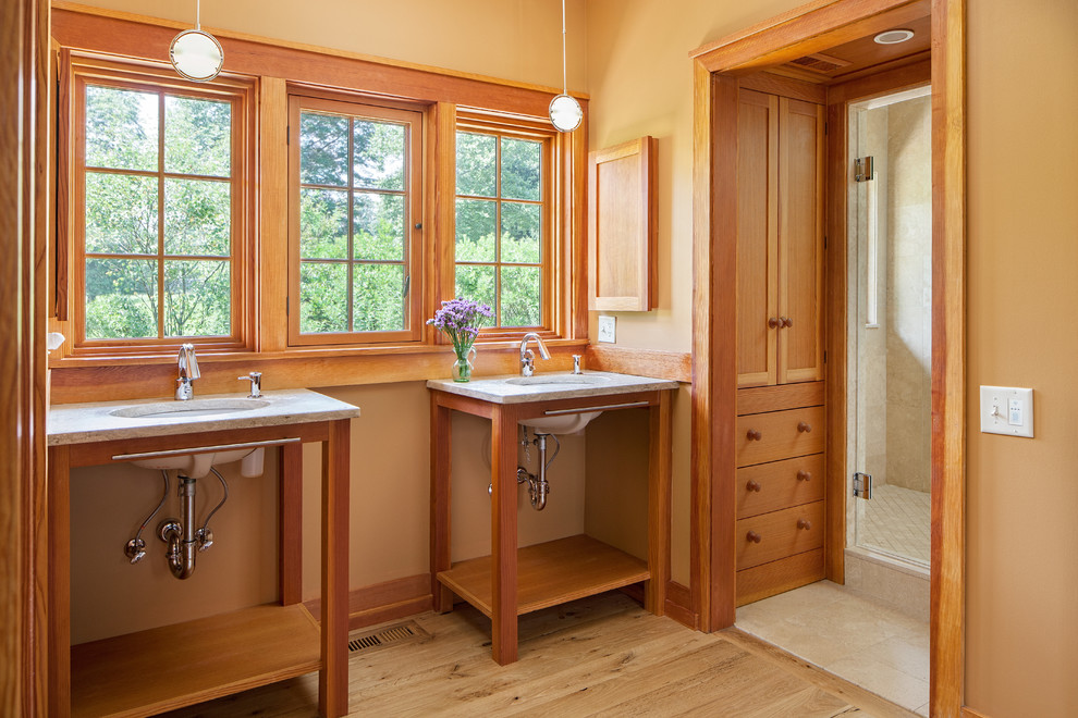 Amerikansk inredning av ett badrum, med ett undermonterad handfat, skåp i mellenmörkt trä, en dusch i en alkov, gula väggar, ljust trägolv och öppna hyllor