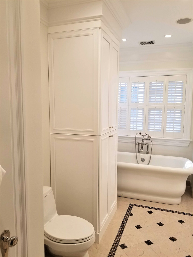 Inspiration for a medium sized traditional ensuite bathroom in New York with recessed-panel cabinets, white cabinets, a freestanding bath, an alcove shower, a one-piece toilet, yellow tiles, yellow walls, porcelain flooring, a submerged sink, engineered stone worktops, beige floors, a hinged door and beige worktops.