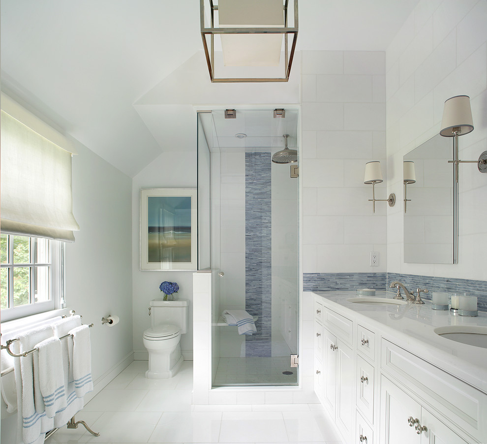 Foto på ett stort vintage vit en-suite badrum, med ett undermonterad handfat, luckor med infälld panel, vita skåp, en dusch i en alkov, en toalettstol med separat cisternkåpa, blå kakel, stickkakel, marmorbänkskiva, vita väggar och klinkergolv i keramik