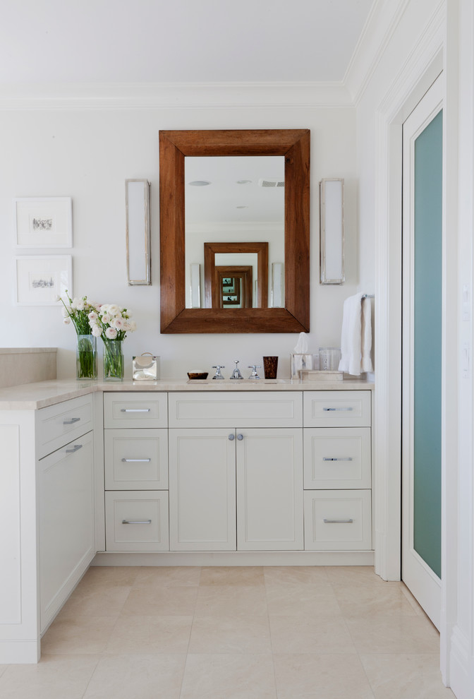 Foto de cuarto de baño rectangular clásico con lavabo bajoencimera, armarios con paneles empotrados, puertas de armario blancas y paredes blancas