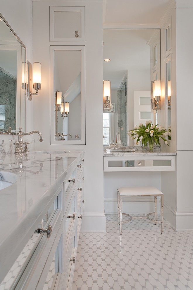 Klassisk inredning av ett stort vit vitt en-suite badrum, med marmorbänkskiva, vita skåp, vit kakel, glaskakel, vita väggar, klinkergolv i keramik, ett undermonterad handfat, vitt golv och luckor med infälld panel