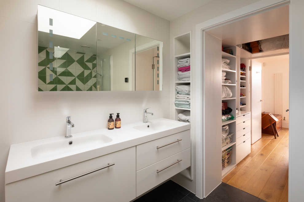 Photo of a medium sized contemporary shower room bathroom in London with flat-panel cabinets, white cabinets, white walls, porcelain flooring, an integrated sink, black floors and white worktops.